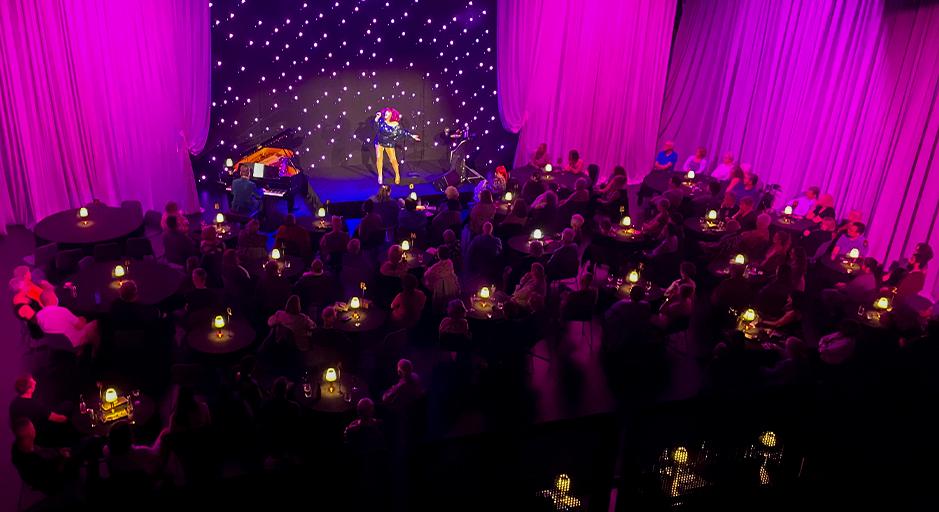 Geraldine Quinn performs on stage at The Round, surrounded by audience seated cabaret style. 